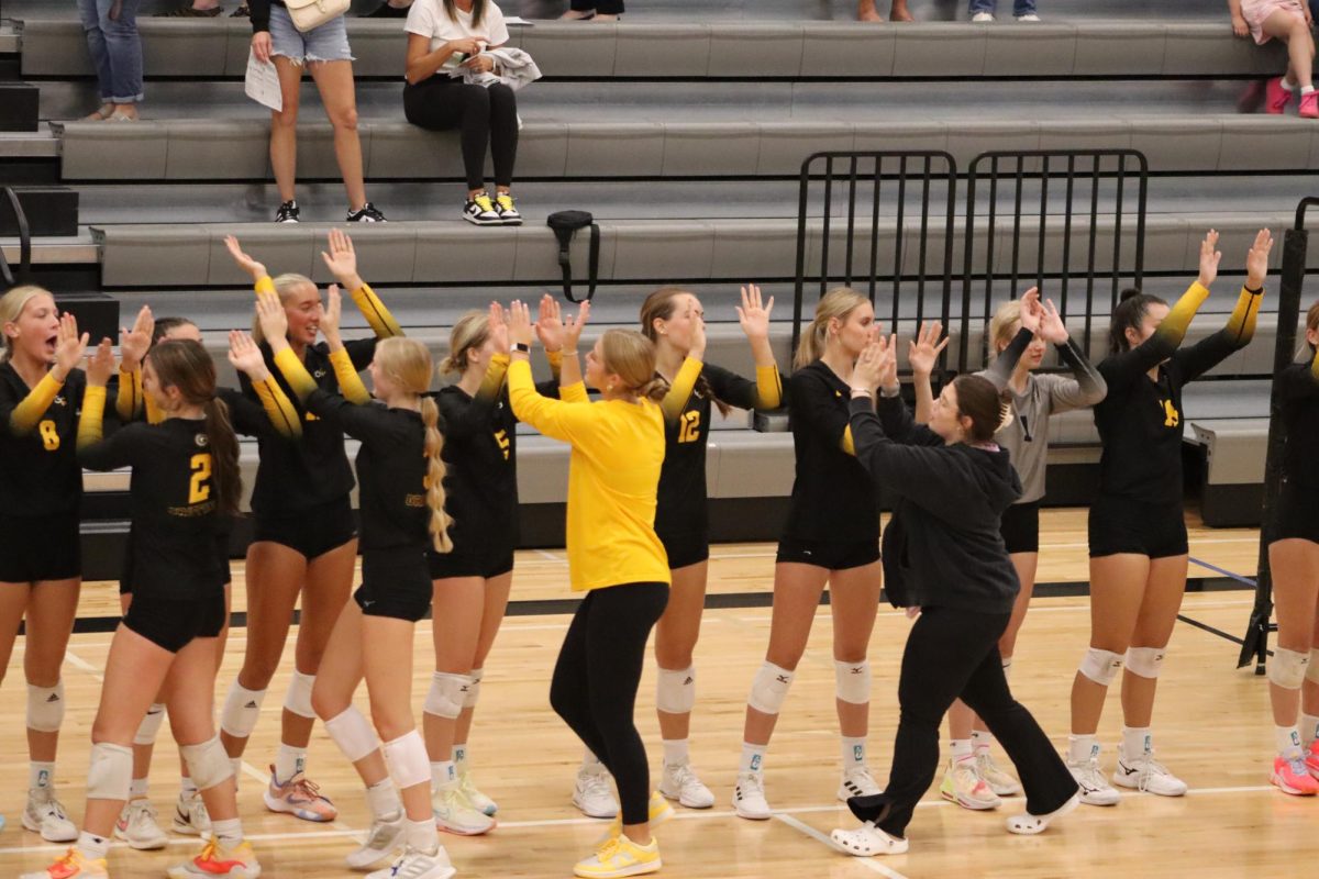 Celebrating their victory, Varsity volleyball players high-five one another.