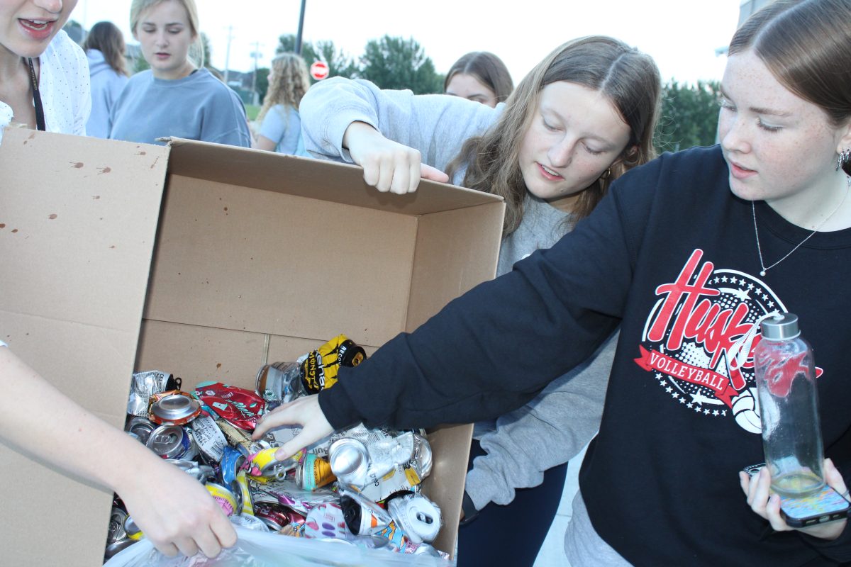 After stomping cans, Avery Johnson (11) and Cece Hansen (11) scoop the waste into a trash bag to recycle.