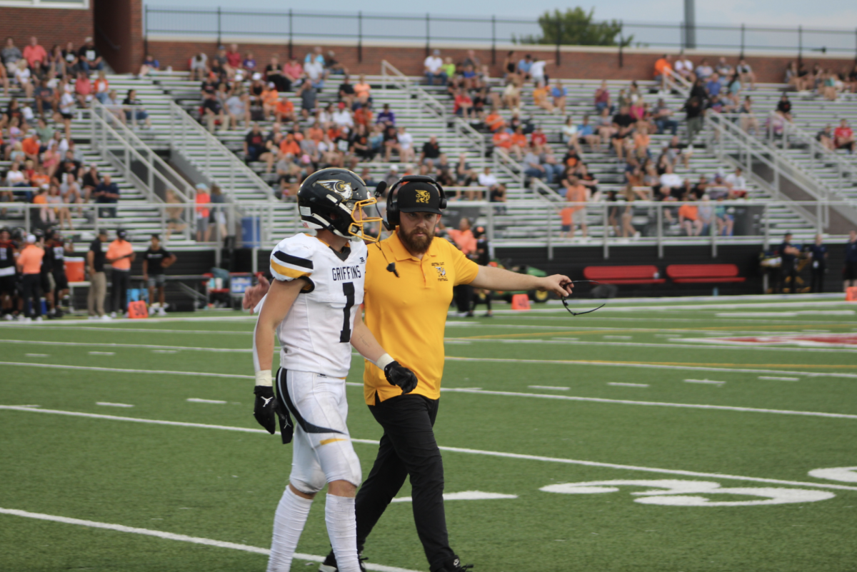Walking off the field, coach Matt Shrader and Grayson Fisher (11) discuss the previous play.