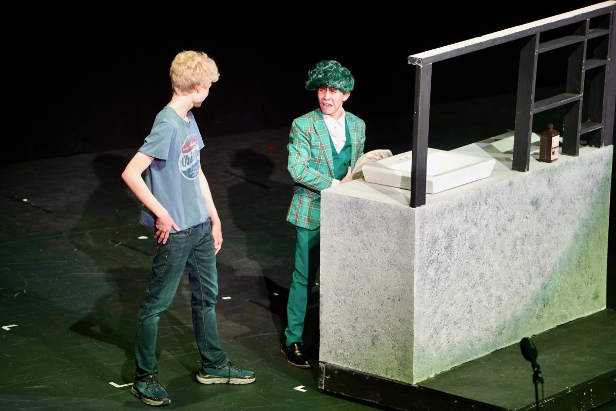 Before realizing his hair is green, Mr. Wormwood, played by Colton Knott (11) lectures his son, Micheal, played by Josh Chase (11), about how his hair is good for a businessman. 