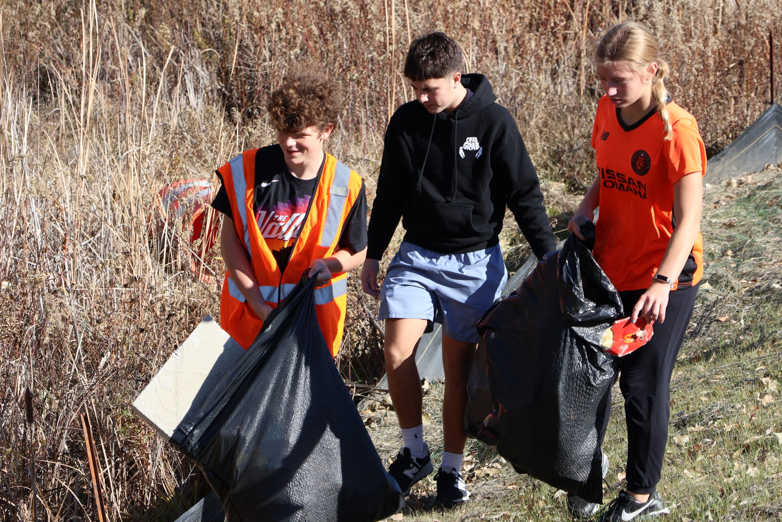 Alongside Highway 370,  FBLA members, Drew Vetter (11), Aiden Stoakes (11) and Camryn Reeson (11), work together to pick up litter.