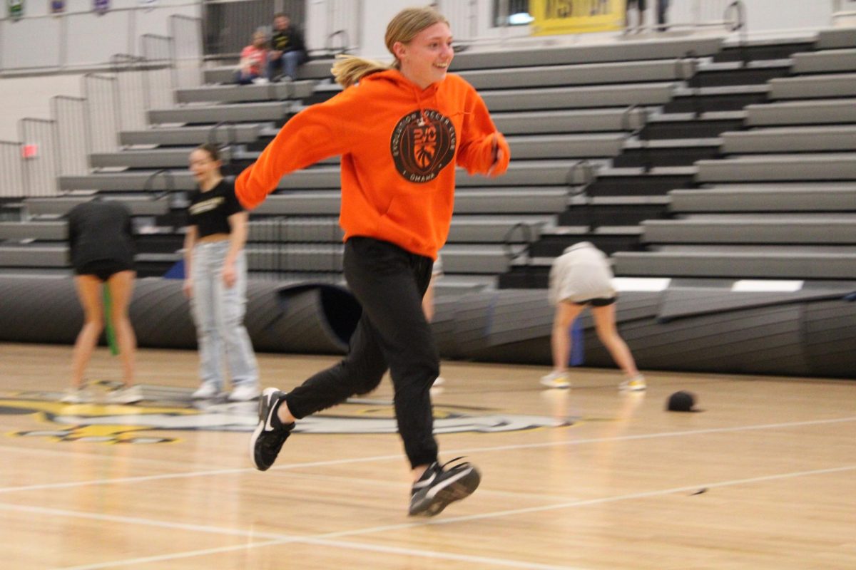 Participating in the class competition dizzy bat, junior Camryn Reeson runs through the gym after spinning in circles on the bat. The junior class ended up winning the competition at the pep rally last night.