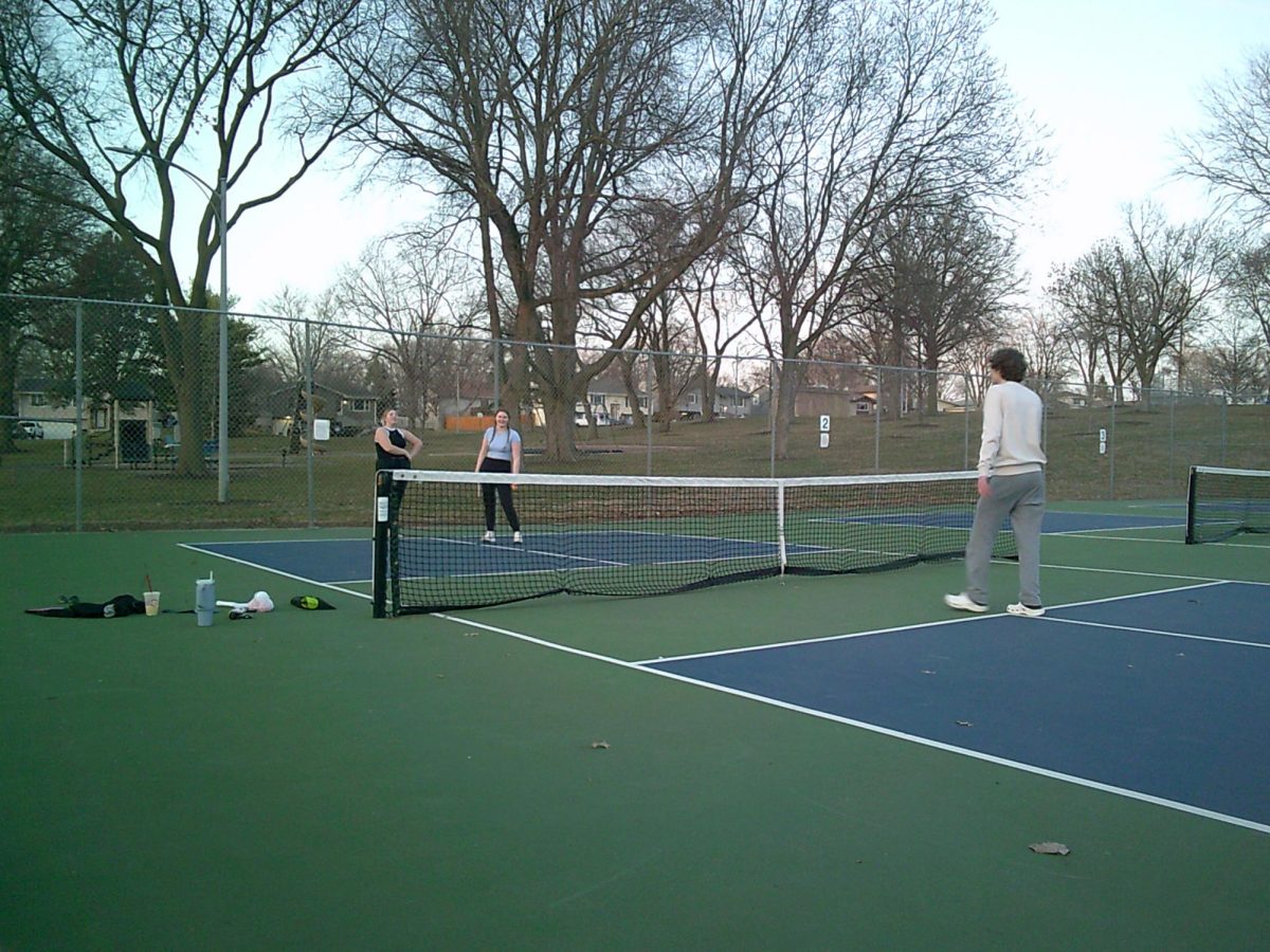Laughing with friends, sophomores Kate Gudenrath, Madeline Petrick and Brayden Hansen compete in a friendly match of pickleball at the North Park courts on March 10. 