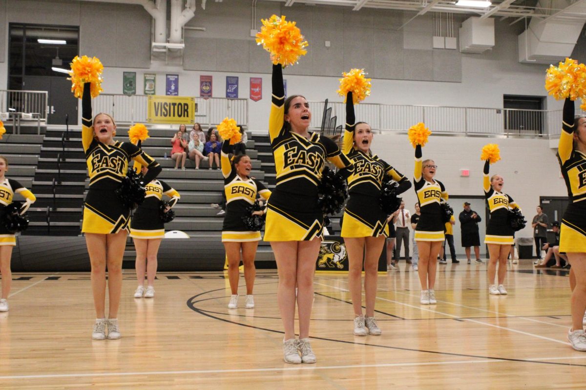 Pointing their poms into the sky, the varisty cheer team performs to begin the spring pep rally on March 12.