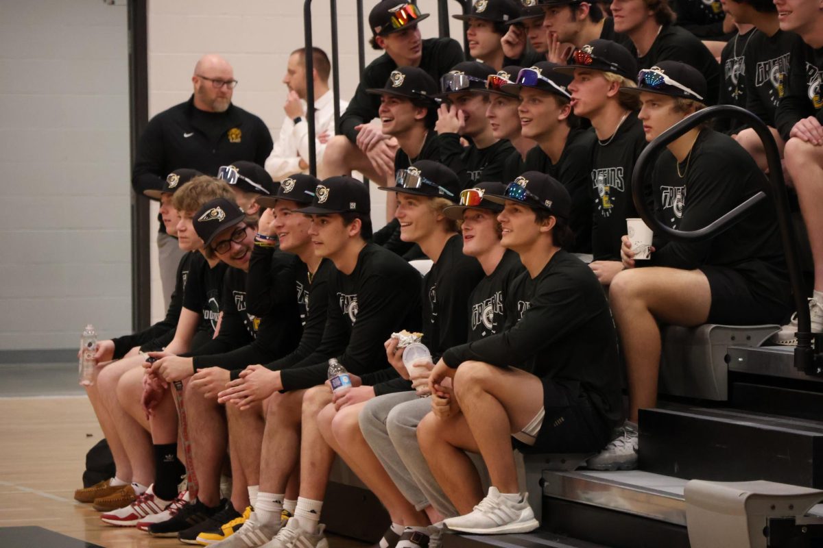 Watching their teams pep rally video, varsity baseball players smile and laugh with one another at the spring pep rally.
