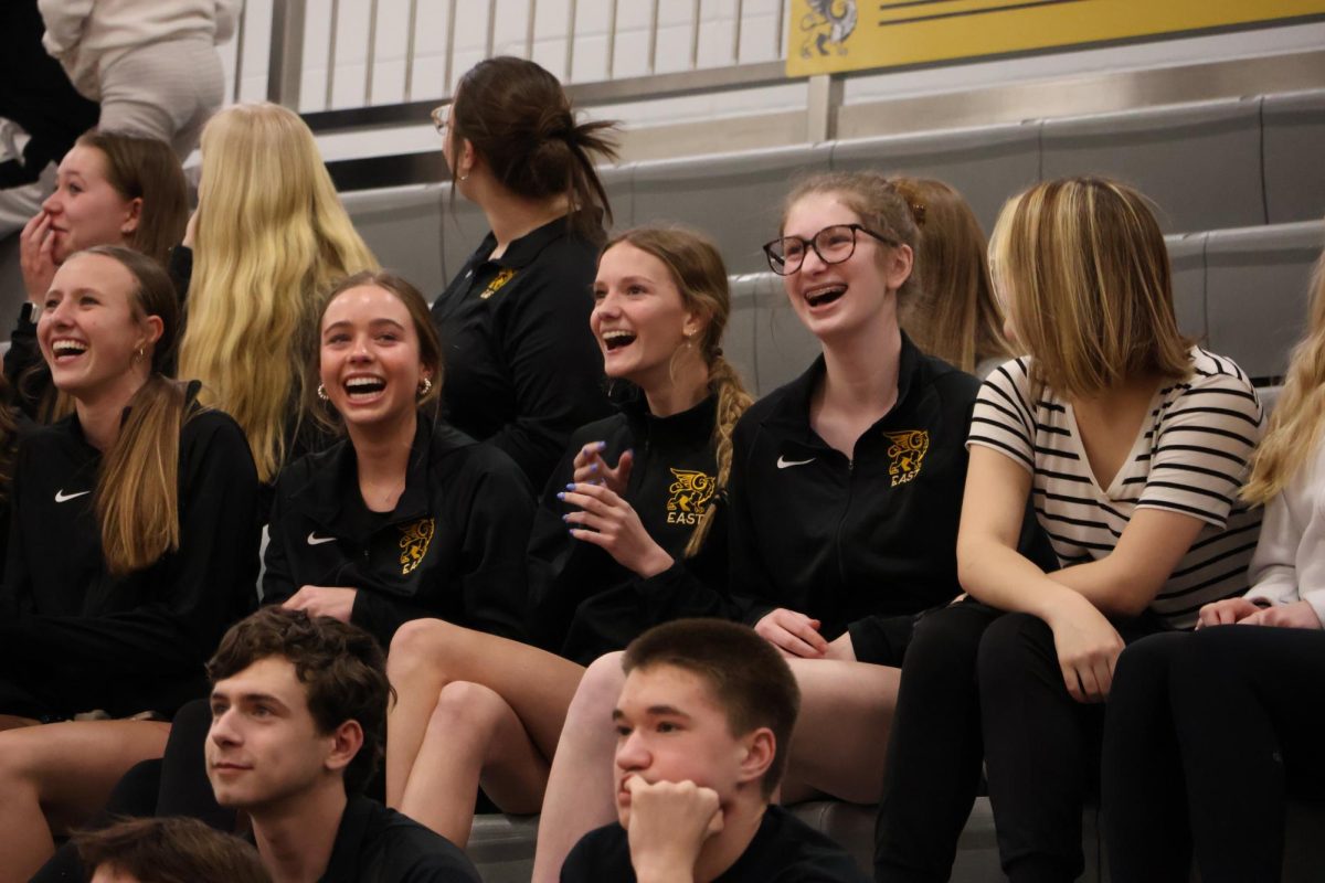 Watching their teams pep rally video, varsity track athletes laugh with one another at the spring pep rally.