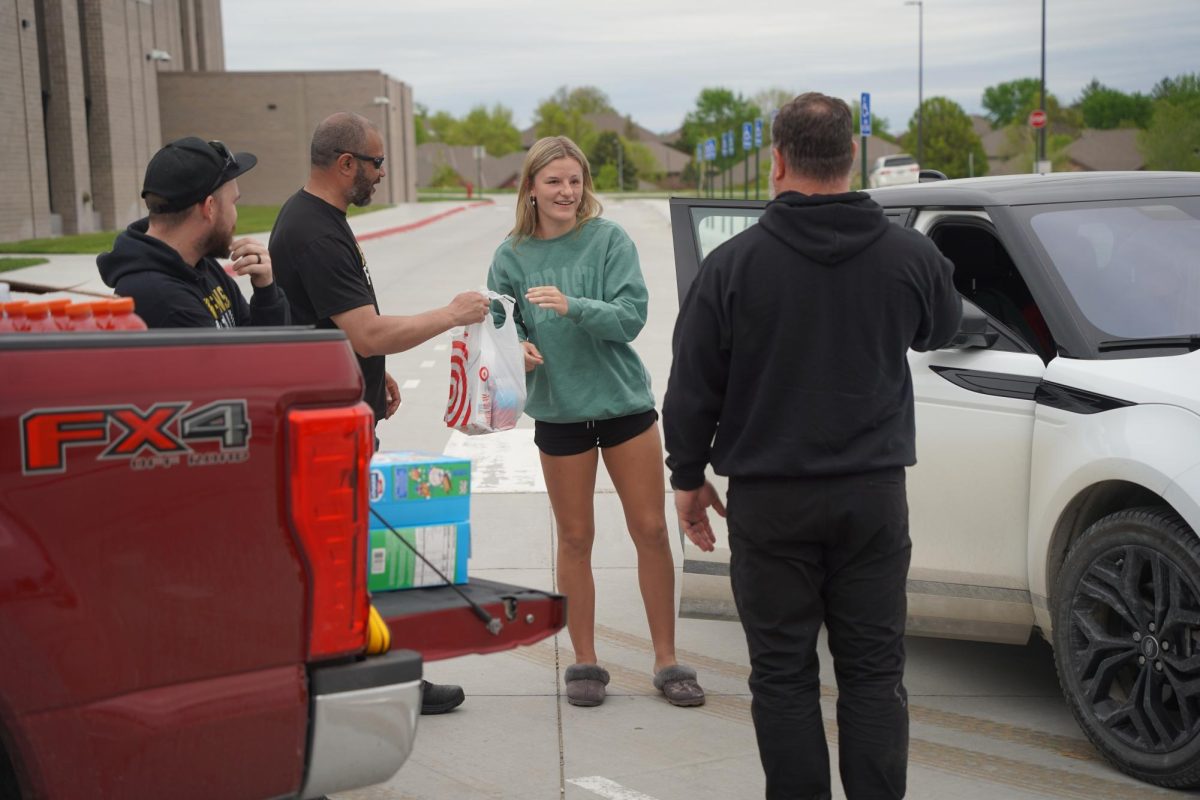 Having a conversation with the football boosters, freshman Avery Kelsay drops off donations.