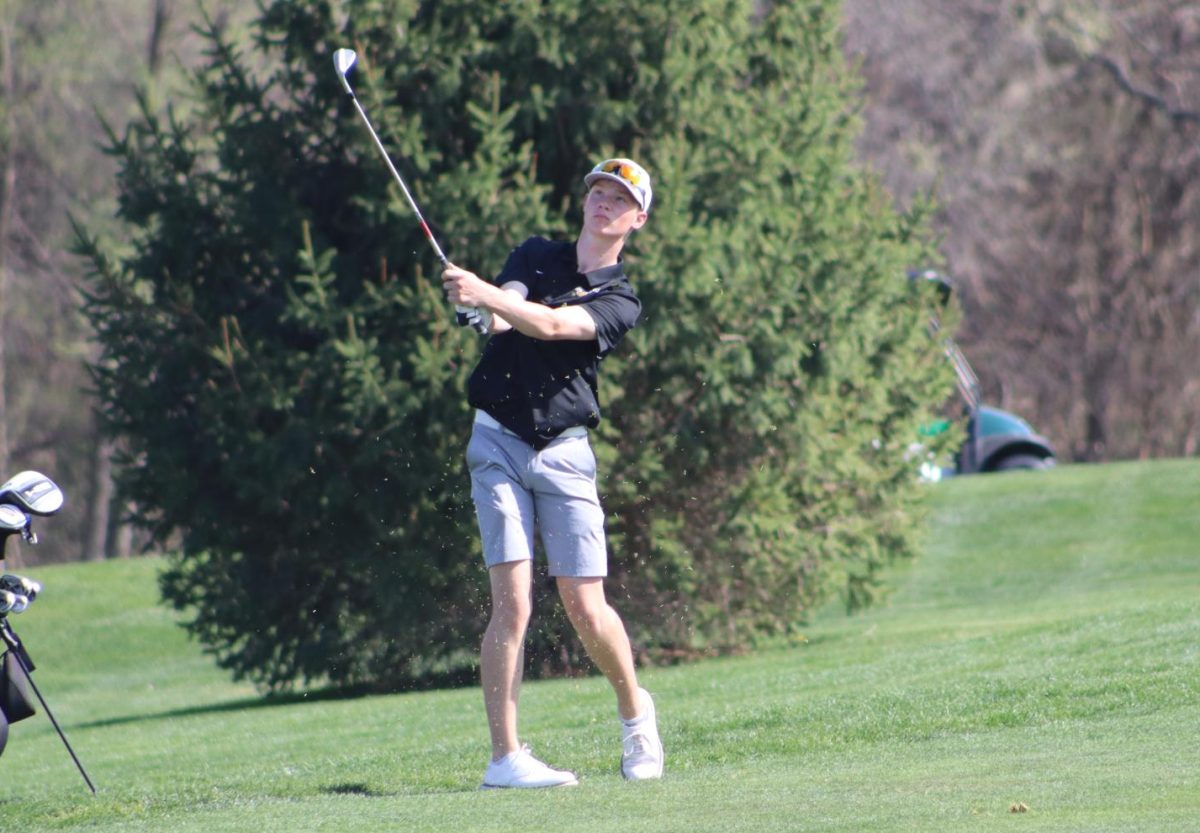 Chipping from the fairway, junior Cole Edwards looks to finish the hole strong against Arlington High School.