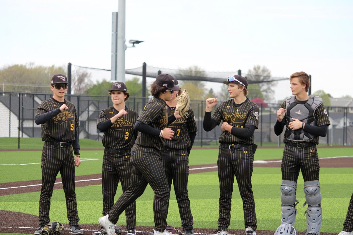 Before the opening pitch, Teammates Tyler Cox (11), Curran Boswell (11), Nolan Green (11), Nolan Iverson (10), and Colton Nicholson (10) share fist bumps while lining up for the National Anthem.
