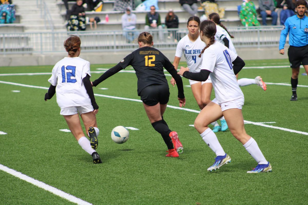 Sneaking in between the Blue Devils players, junior Kendall Dobberstein pushes the ball towards the goal. 