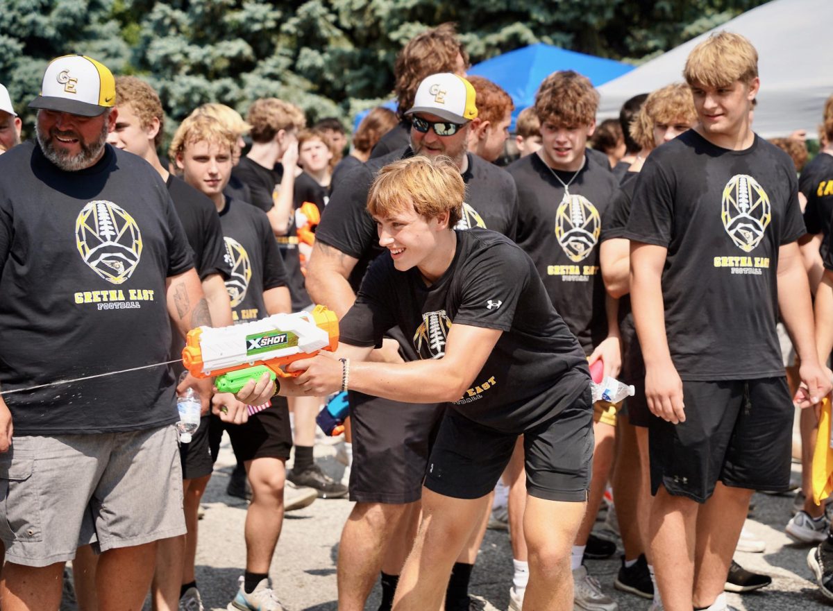 Representing the GEHS football team, senior Luke Johnson sprays children on the side of the street with a water gun. 