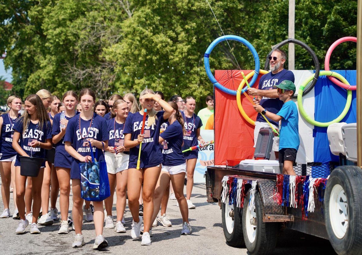 Using a water gun, head volleyball coach Mike Brandon sprays parade attendees as a part of the Gretna East volleyball float. 