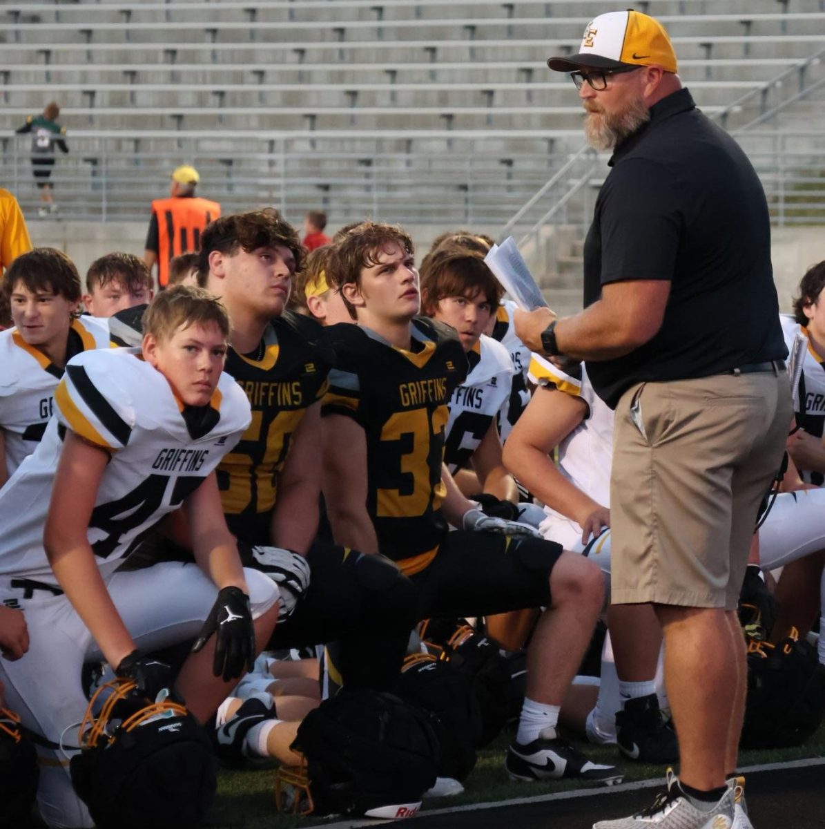 Bridging both sides of the Aug. 23 scrimmage, head coach Justin Haberman talks to all the athletes, regardless of which side they are on during half time in the south endzone. 