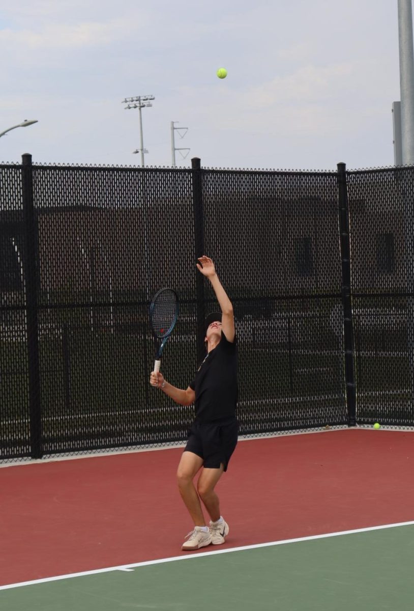 Keeping his focus on the ball, senior Braden Dall gets athletic in his serve. Dall lost a point from this serve by hitting it into the net.