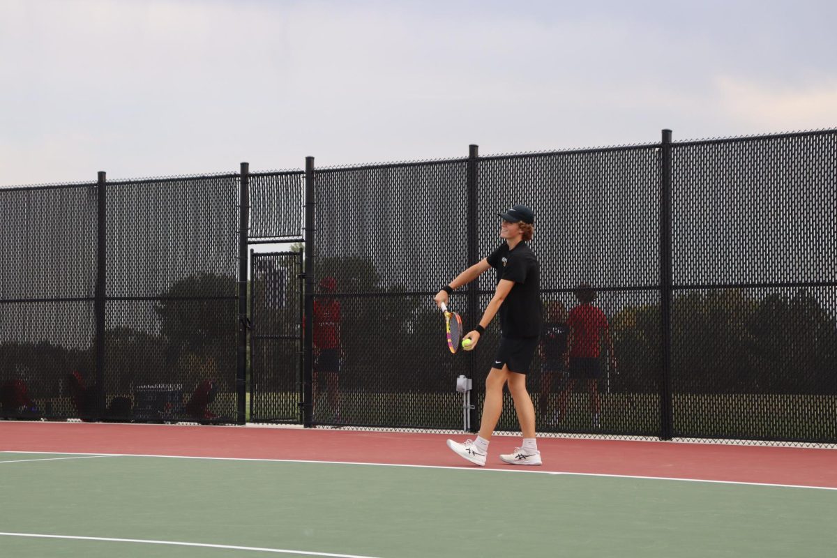 With his eyes set on his opponent, senior Rylan Wobken tosses the ball up in the air before his serve. Wobken later won his match 8-0. 