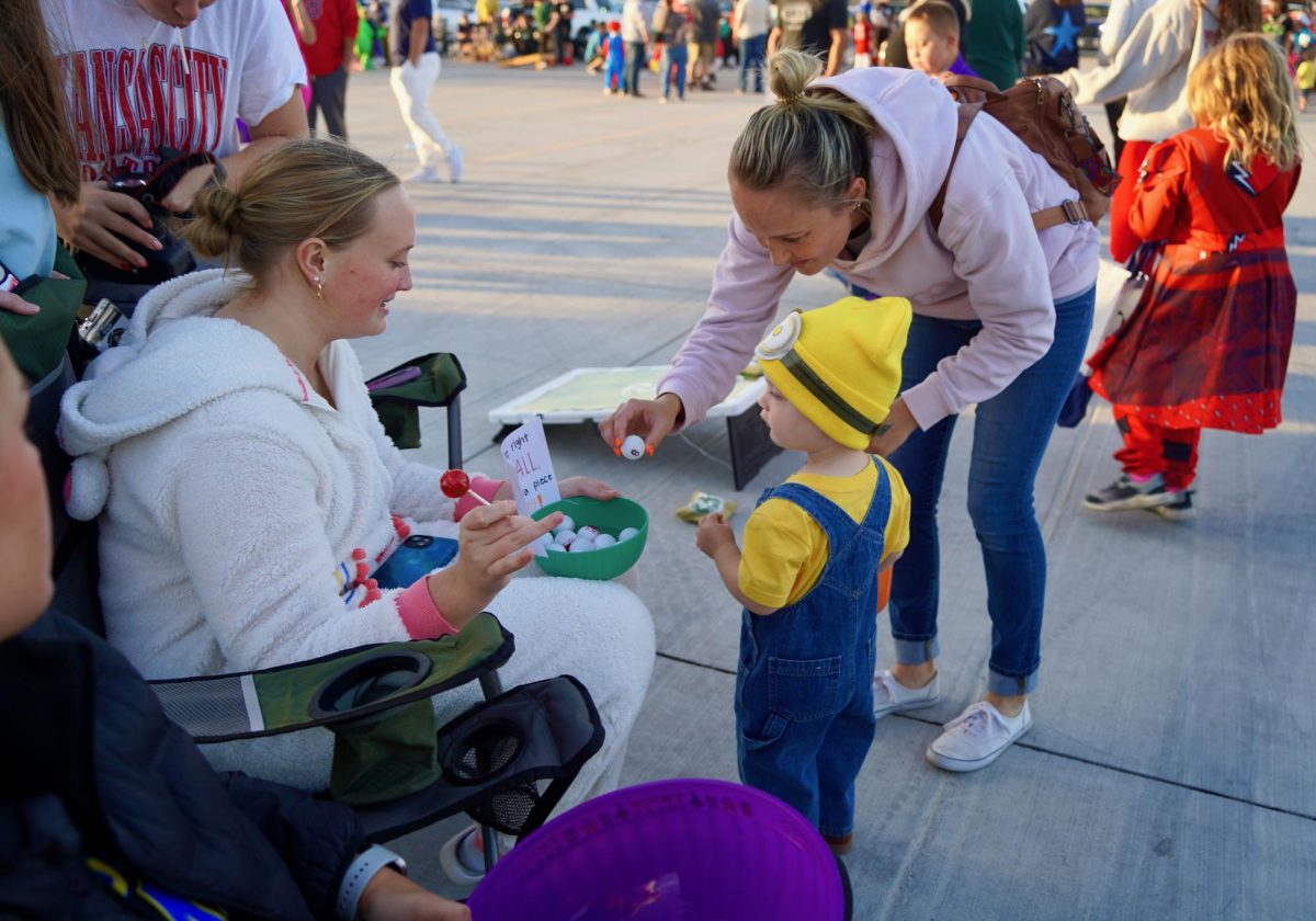 Holding up a plastic eyeball, a Trunk-or-Treater shows junior Morgan Zabloudil the number written on it. Participants would pick an eyeball from the bowl and had to find the correct number to earn an extra piece of candy. 