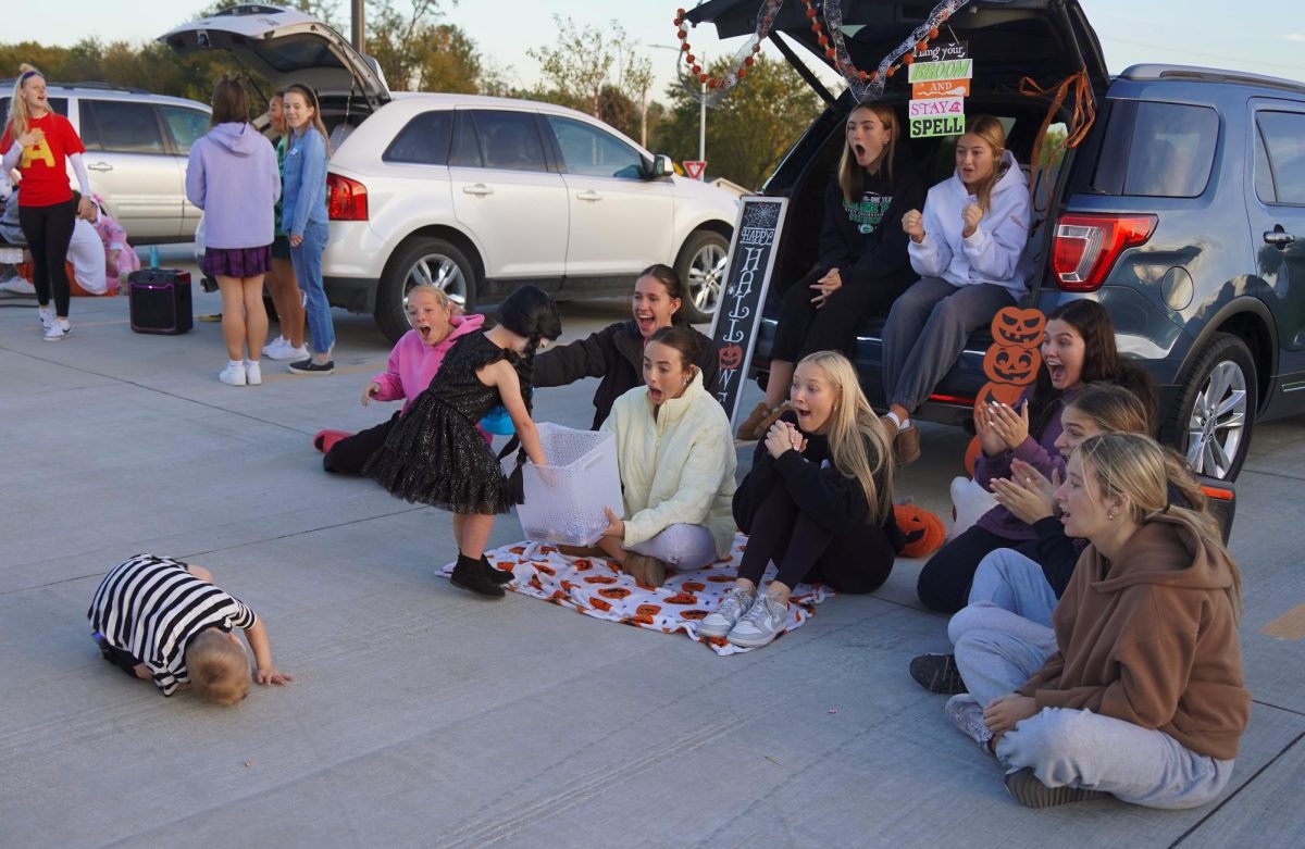 Sitting in front of their Halloween-themed trunk, this group watches as a Trunk-or-Treater does a sommersault in order to get an extra piece of candy. Participants could "show their dance moves" for extra candy.  