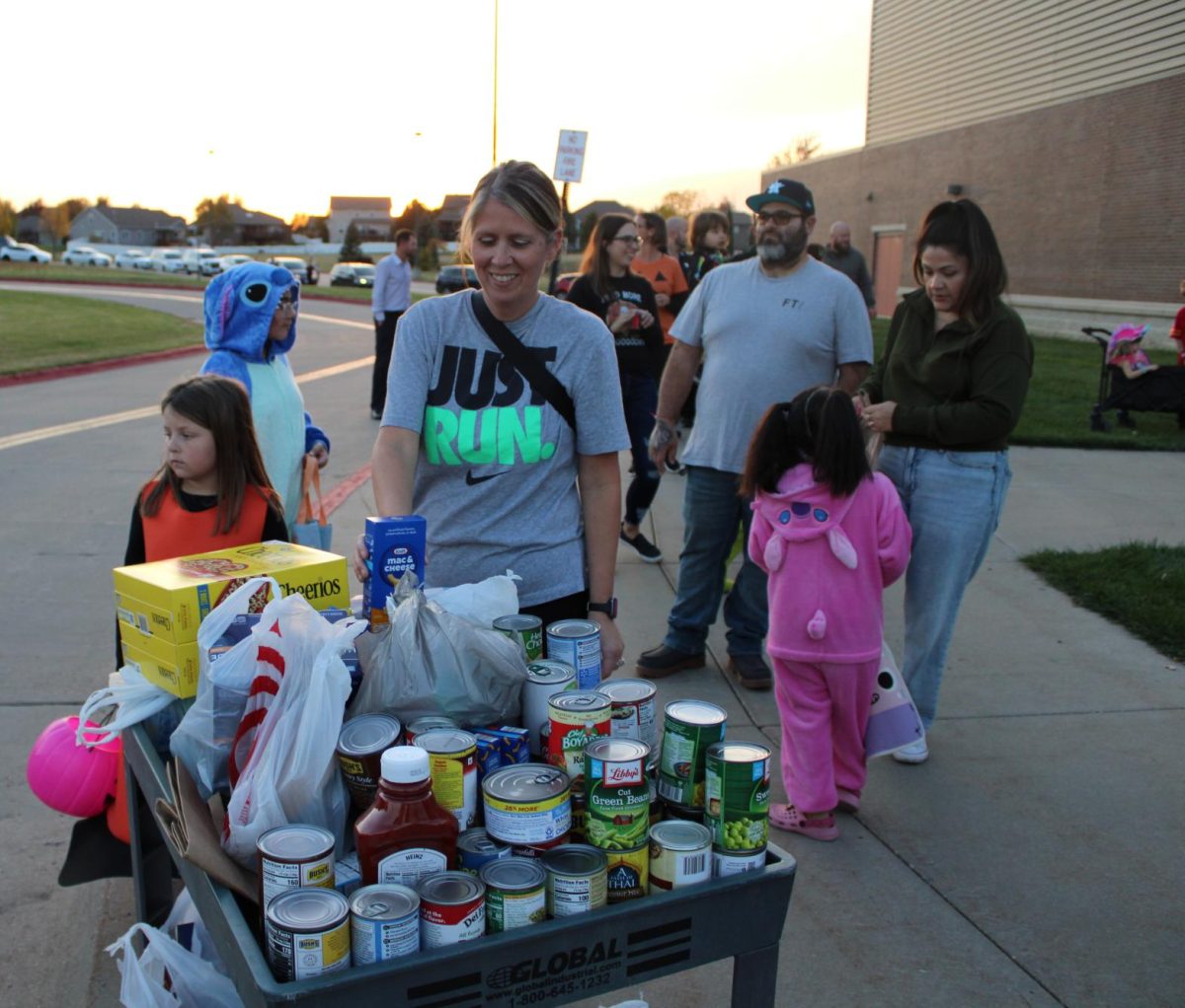 Unloading her donations onto the cart, community member Aimee Hansen smiles. The cart was overflowing with donations for the Gretna Neighbors food pantry, with many bringing more than the required two cans in order to enter.