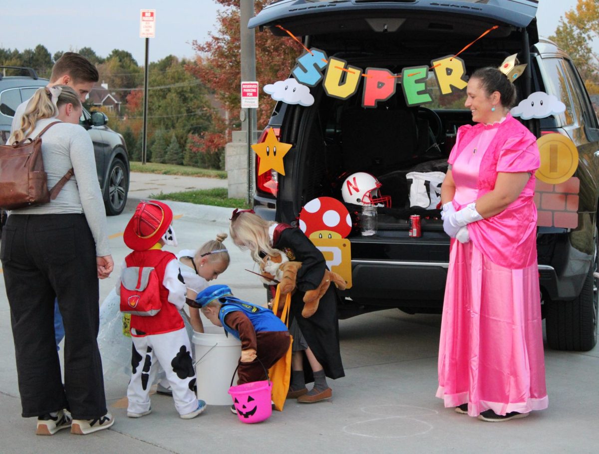 Decked out in a Princess Peach costume, community member Dusti Henrichs smiles as Trunk or Treaters enjoy her Mario themed trunk. Three different trunks at the Palisades Trunk or Treat on Oct. 24. had a Mario theme.