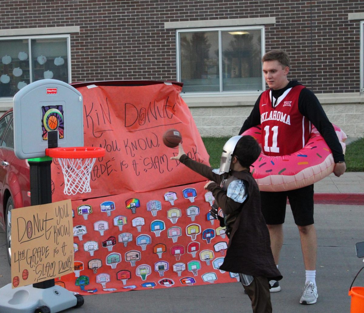 Instructing each Trunk or Treater how to play, fourth grade teacher Logan Holle watches as a kid dressed as the Mandalorian shoots and scores. The fourth grade trunk was very popular at the Palisades Trunk or Treat for its theme: Dunkin' Donuts.