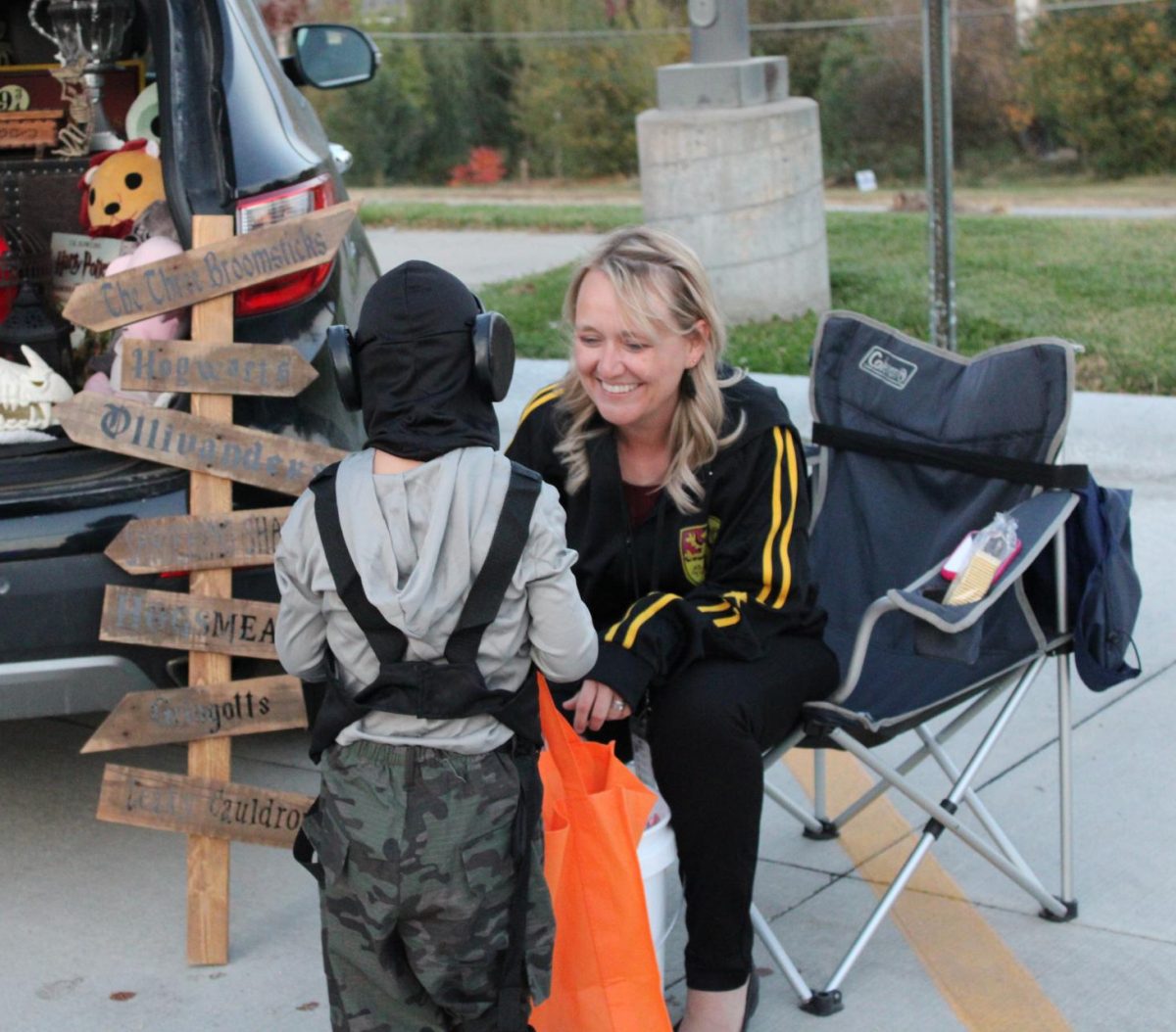 Sitting in front of her Harry Potter themed trunk, principal Karen Naylor gives a handful of candy to the Trunk or Treater. Naylor's trunk was popular at the Palisades Trunk or Treat due to its clever theming. 