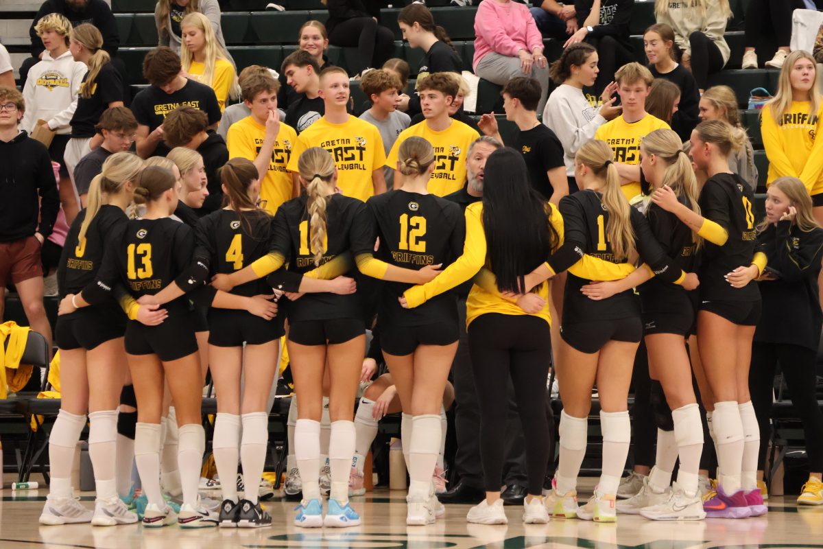 During a timeout, the varsity volleyball team huddles around head coach Mike Brandon. They discuss plays and tactics to use when the game resumes. The Griffins won 3-1 against the Gretna Dragons on Oct. 15.