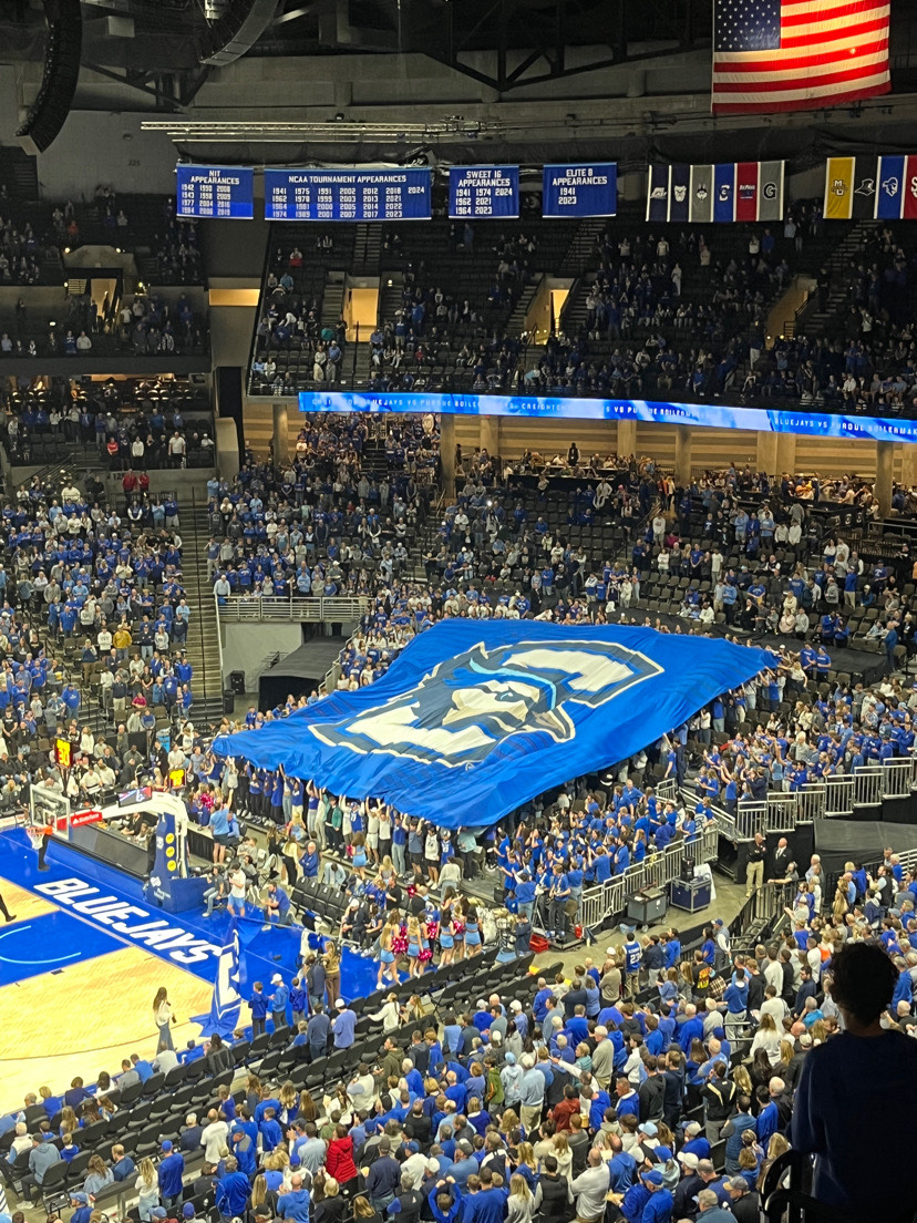 Before tip-off in an exhibition between Creighton and Purdue, the student section spreads a flag showing the Bluejay logo.