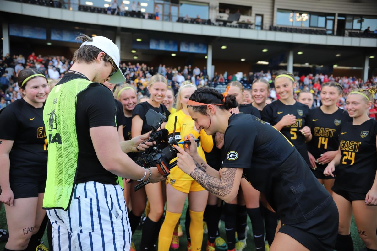 After beating Duchesne in the NSAA Class B Girls State Soccer Championships on May 13, a member of the media has junior Sonora Defini sign the lens of his camera as her teammates cheer her on. 