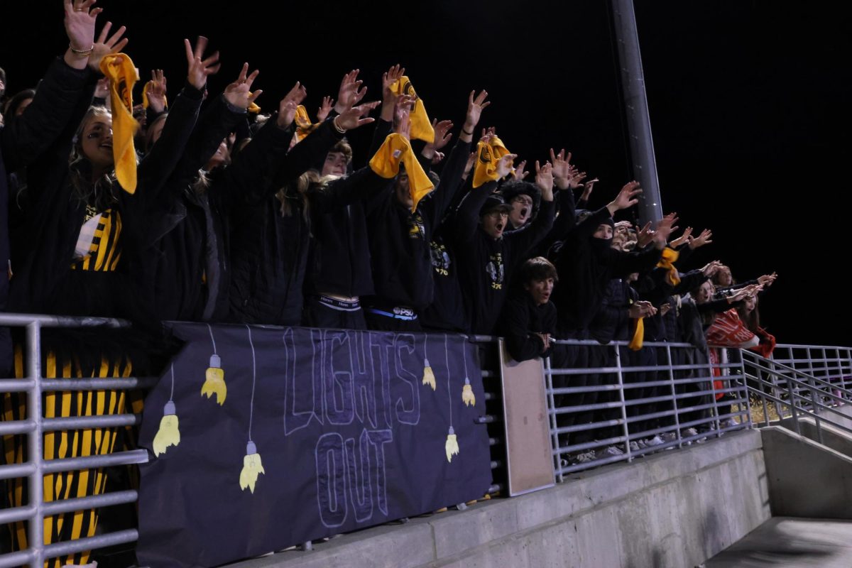 Raising their hands, students cheer for the punt on Oct. 25 during the football game against GHS. The Griffins won this game by a field goal in overtime, 23-20.