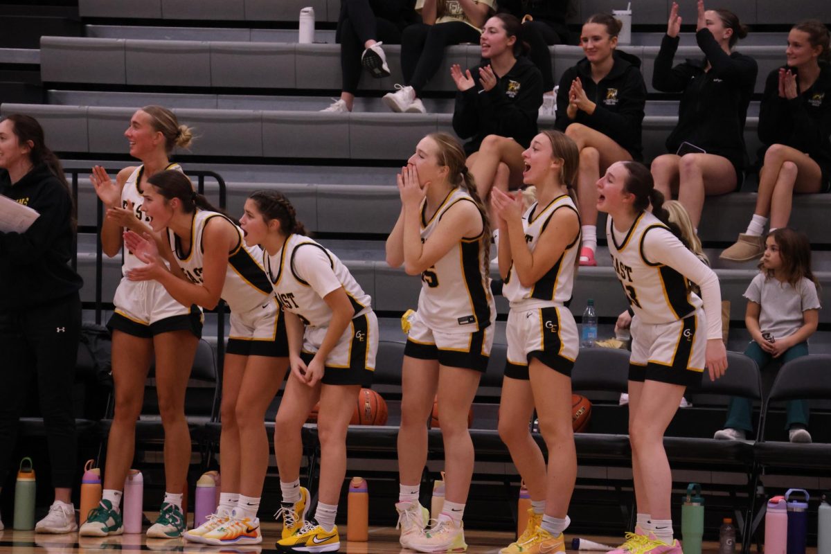 Cheering on their teammates, the varsity girls cheer from the bench as they watch their teammates on the court. The girls claimed their first win of the season against Duchesne scoring 66-21.