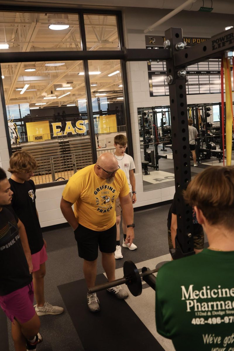 During a weight training class PE teacher, Justin Haberman, helps a student demonstrate.