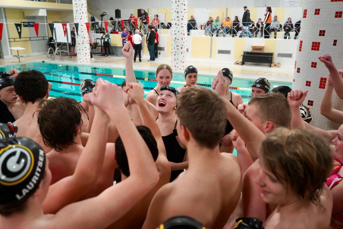 Leading the team chant before their meet against Omaha South on Jan. 7, senior Cecelia Hansen stands in the middle of the swimmers. As a senior, Hansen had always wanted to lead the chant but this was her first opportunity. 