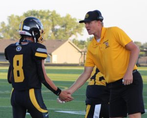 Coming off the sidelines, Assistant Coach Sean McLaughlin high fives his players after a play. The Griffins won 63-6 against the Buena Vista Bison.