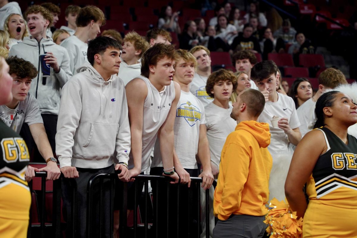 Before the second half of the girls basketball State finals, Activities Director Ryan Garder talks to students at the front of the student section. 