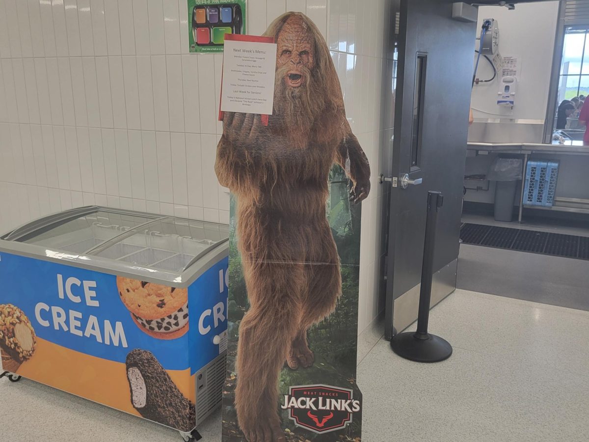 The mascot of the cafeteria, a sasquatch, stands by the ice cream freezer on Friday, May 2 at lunchtime. He holds the schedule for next week's menu in his right hand.