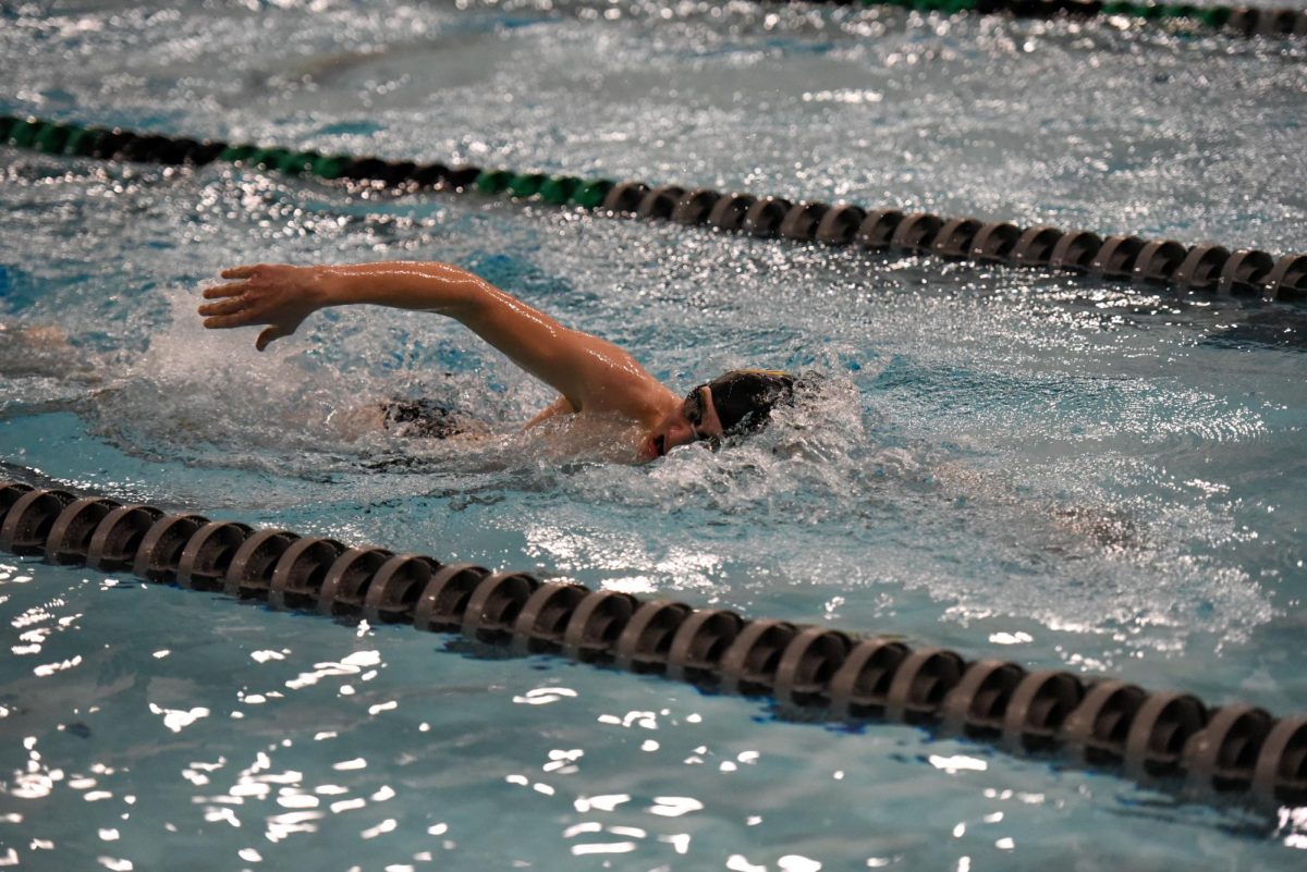 Powering through the water, freshman Beckham Green swims freestyle during a 100-meter race. Green placed second with a time of 00:56.34—only three seconds behind first place.