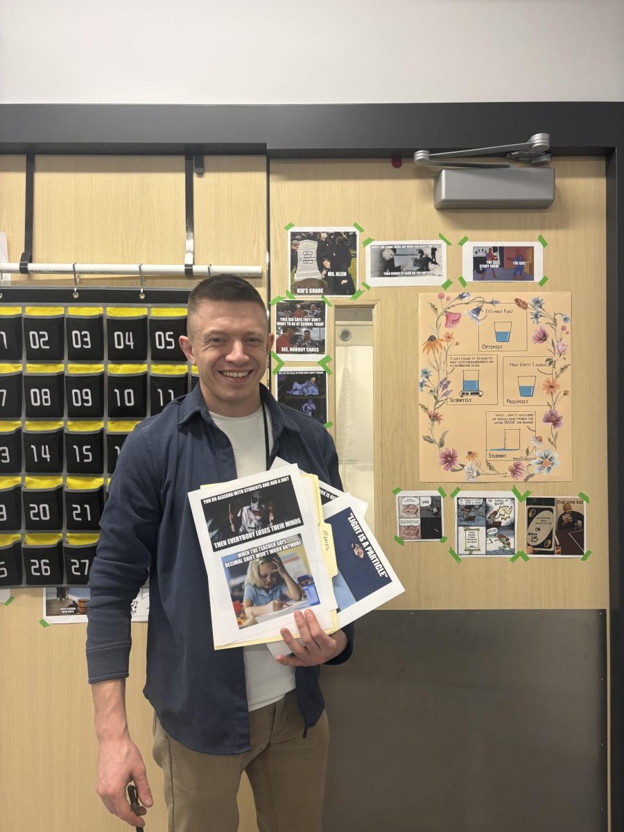 Jacob Klein poses in front of his wall of memes. 
