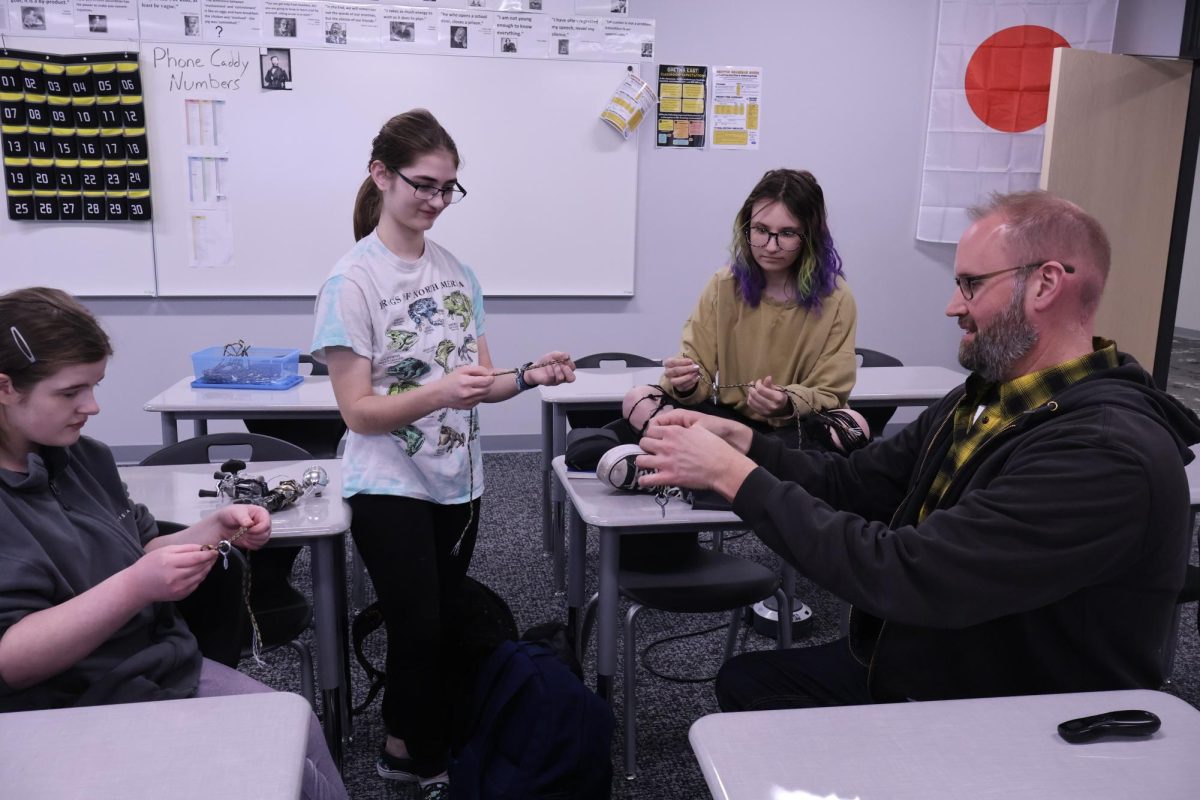 Fishing club sponsor Nathan Geiken ties a fishing knot at the first fishing club meeting as juniors Katelyn Clayton, Claire Conoan and Sydnee Barr try to replicate it.